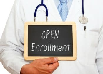 doctor holding chalkboard reading "open enrollment"