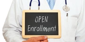 doctor holding chalkboard reading "open enrollment"