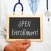 doctor holding chalkboard reading "open enrollment"