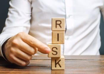 "risk" spelled in vertical wooden blocks with man removing one block