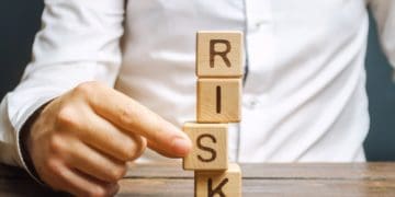 "risk" spelled in vertical wooden blocks with man removing one block