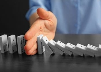 woman's hand stopping falling dominos
