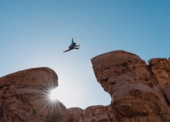 man in suit jumping gap between rocks