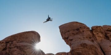 man in suit jumping gap between rocks
