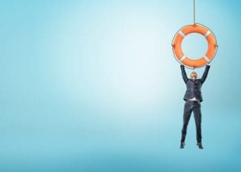 businessman hanging by his hands from orange life saver
