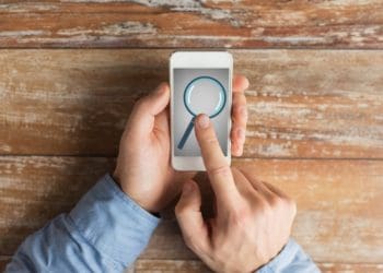 man selecting magnifying glass icon on smartphone