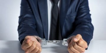 man in navy suit in handcuffs