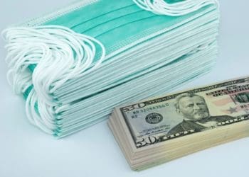 stack of cash beside stack of medical masks