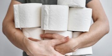 man holding multiple rolls of toilet paper