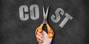 hand with scissors cutting the word "cost" in half