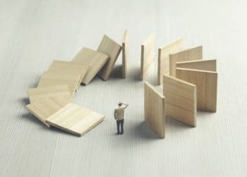 dominos falling around businessman