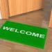 green welcome mat outside office door