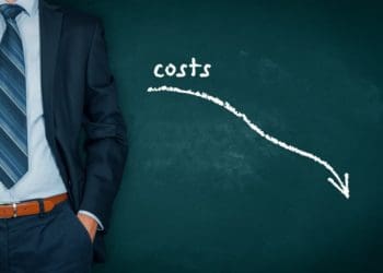 man by chalkboard with costs and downward pointing arrow