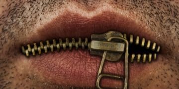 closeup of man's mouth with metal zipper keeping lips closed
