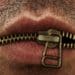 closeup of man's mouth with metal zipper keeping lips closed