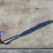 aerial view of worker in hi-vis jacket holding clipboard with long shadow