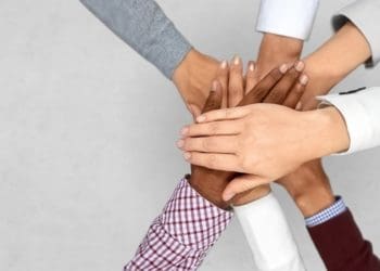 ethnically diverse group of people with hands in a huddle