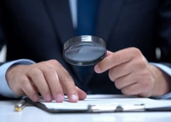 man studying report with magnifying glass