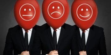 businessmen holding red balloons with various emoji faces