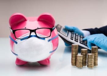 piggy bank wearing mask and glasses, gloved hands punching numbers into calculator