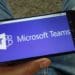 Man holding smartphone with Microsoft Teams communications platform logo