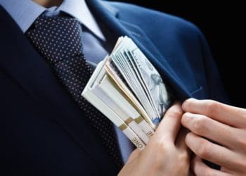 businessman pocketing stacks of cash