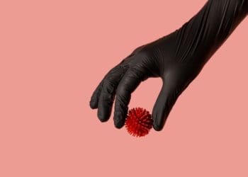 hand in black glove holding model of coronavirus