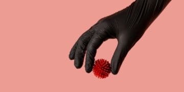 hand in black glove holding model of coronavirus