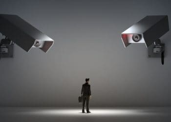 two large security cameras pointed at man in spotlight