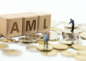 AML in wooden blocks with figures standing on coins