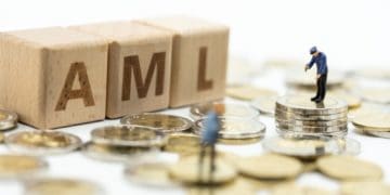 AML in wooden blocks with figures standing on coins