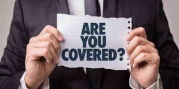 man in suit holding "are you covered?" sign
