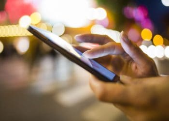 woman using smartphone in the street, city lights in background