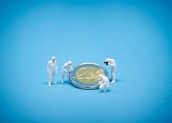 tiny figures in forensic protective gear inspecting Euro coin