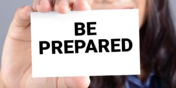 woman holding card that reads "be prepared"