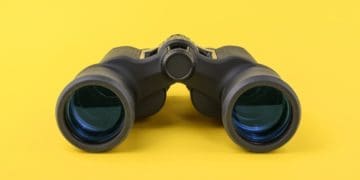 black binoculars on yellow background