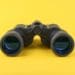 black binoculars on yellow background