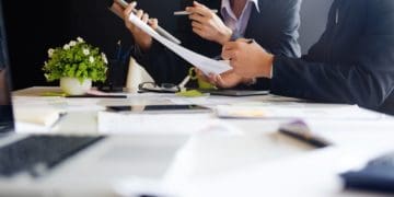 man and woman reviewing reports at conference room table