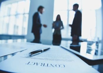 contract in foreground with businesspeople in background