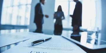contract in foreground with businesspeople in background