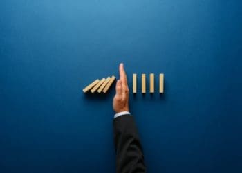 top view of businessman hand stopping falling dominos, concept of crisis management