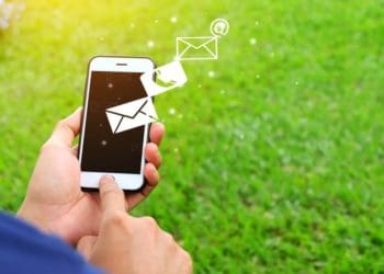 man holding mobile phone against grassy backdrop