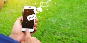man holding mobile phone against grassy backdrop