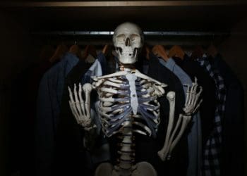 skeleton among clothes in dark closet