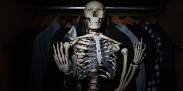 skeleton among clothes in dark closet