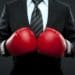 man in suit wearing red boxing gloves