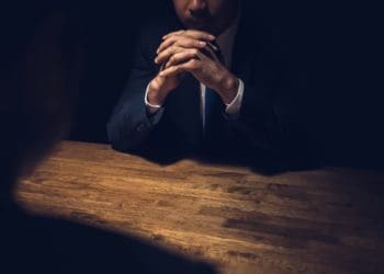 detective sitting in dark room with witness