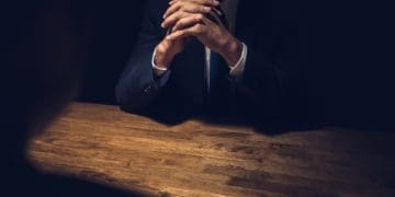 detective sitting in dark room with witness