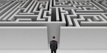 man in suit standing at opening of large maze