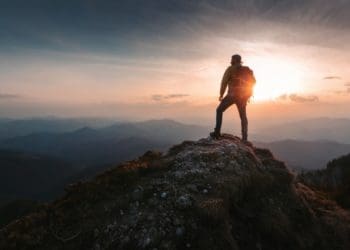 hiker standing on mountaintop at sunrise